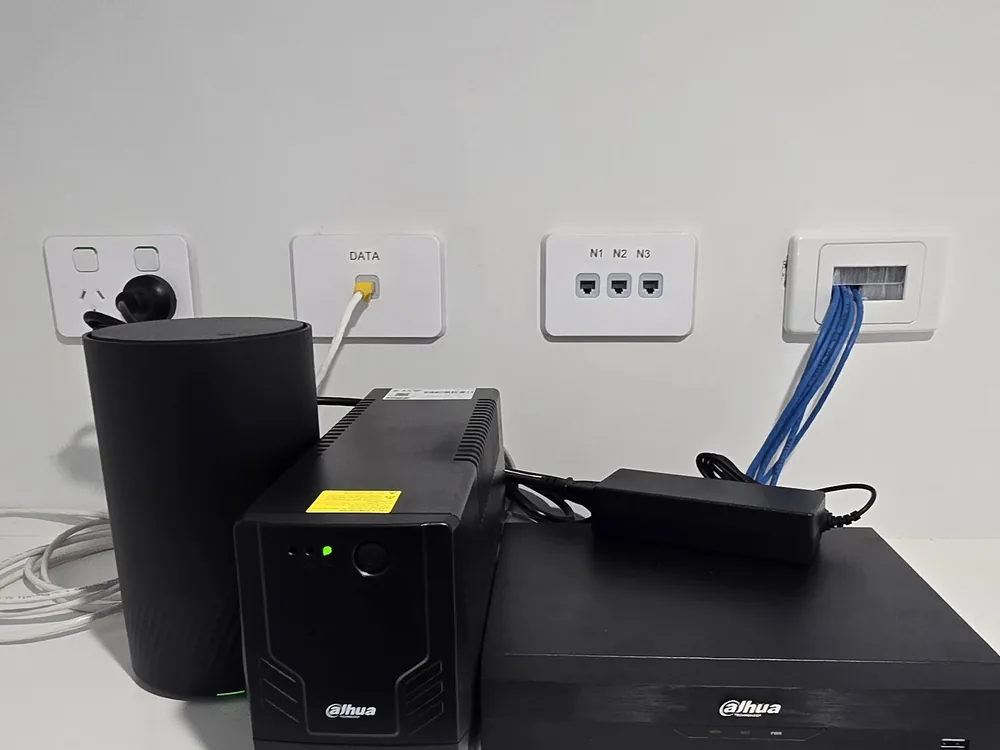 Central CCTV and network equipment Dahua NVR, UPS and modem set up on a desk beside labelled data and network points